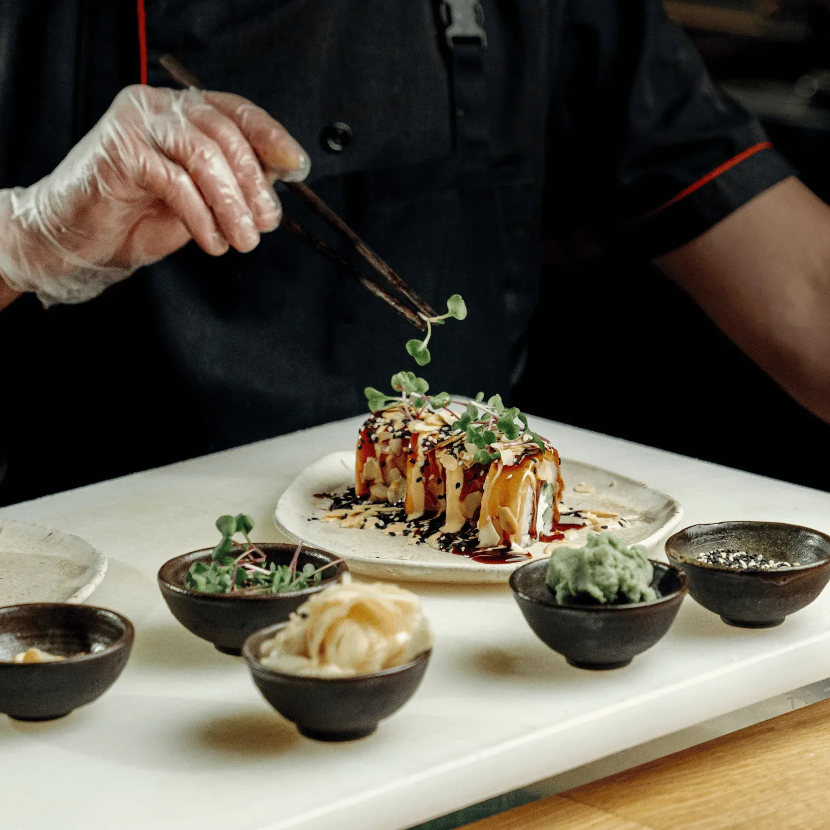 Chef plating gourmet dish with chopsticks