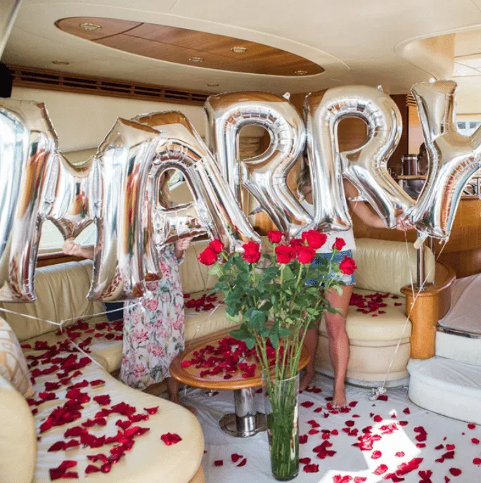 Yacht interior decorated with marry me balloons and roses
